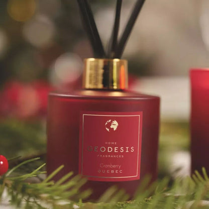 Diffusore Geodesis Cranberry 200 ml su tavolo in legno, con decorazioni natalizie e luci calde sullo sfondo.